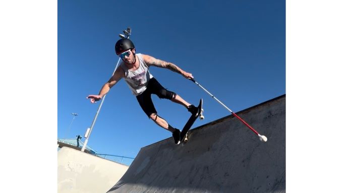 Justin Bishop skateboarding in halfpipe with his white cane